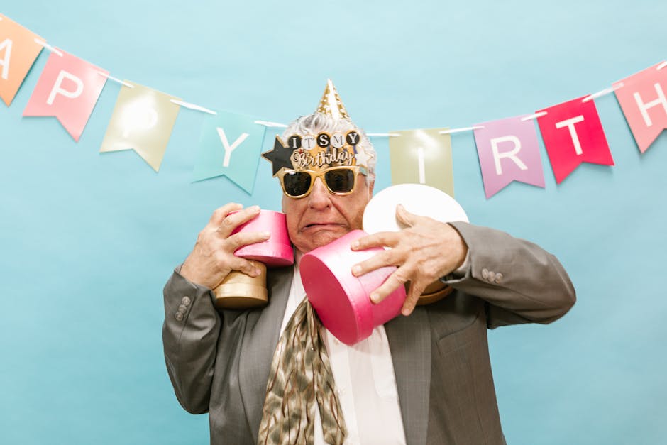 Elderly man joyfully celebrating his birthday with gifts and decorations.