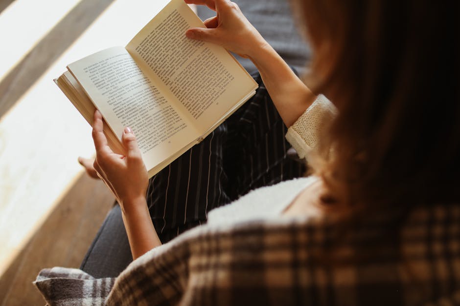 A woman enjoys reading a book while relaxing indoors, capturing a moment of leisure and comfort.