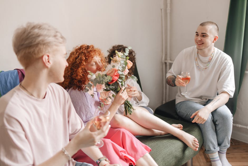Group of LGBTQ friends celebrating indoors with flowers and drinks, capturing joy and inclusivity.