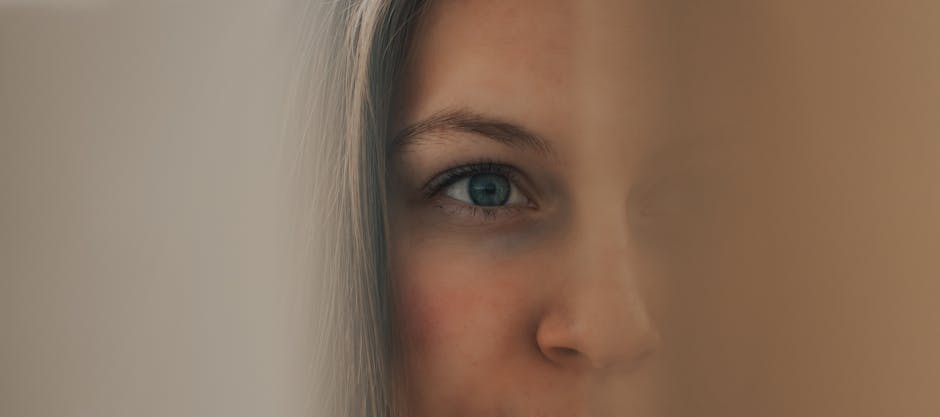 Minimalist close-up of a woman's face partly obscured, focusing on a blue eye.