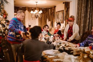 A joyful family gathering around a table decorated for Christmas, sharing food and happiness.