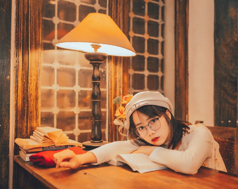 Young woman with eyeglasses reading in a cozy, elegantly lit space, styled with warm tones.