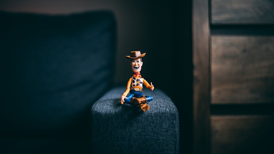 A toy cowboy figurine sits on the armrest of a gray sofa, creating a playful indoor still life scene.
