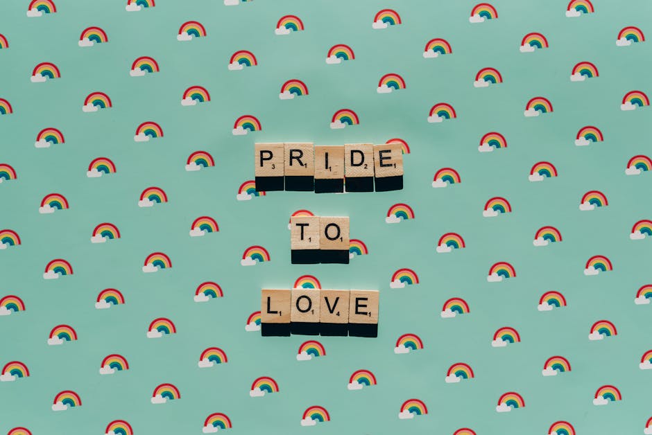 Scrabble tiles spelling 'Pride to Love' on a rainbow background, celebrating LGBT pride.