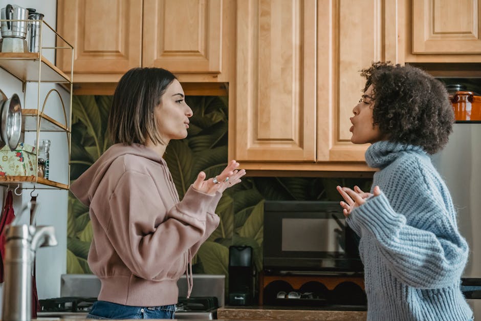 Side view of unhappy young multiracial girlfriends in casual clothes standing in kitchen while having disagreement and lookin