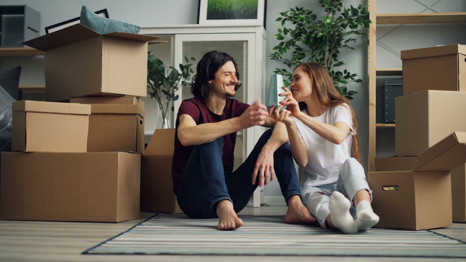 Smiling couple enjoying moving day surrounded by cardboard boxes inside their new home.