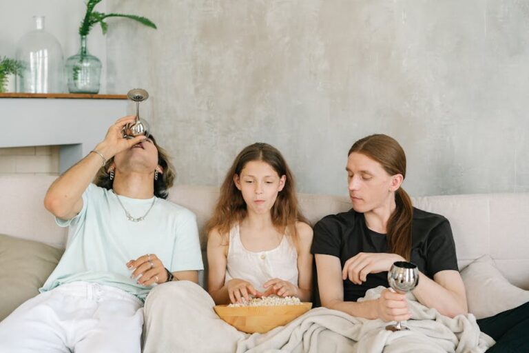 A diverse group of friends enjoying popcorn and drinks together on a cozy indoor sofa.