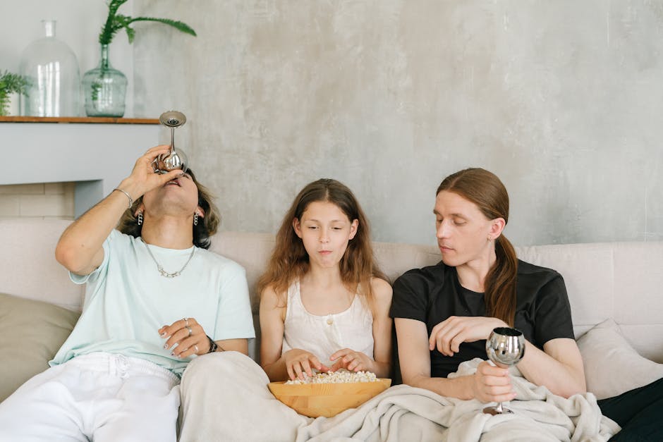 A diverse group of friends enjoying popcorn and drinks together on a cozy indoor sofa.