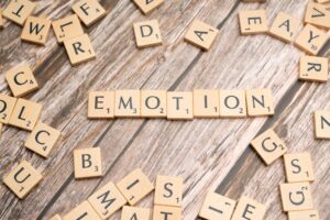 Scrabble tiles forming the word emotion on a wooden background.