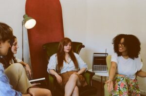Four adults engaged in a relaxed group discussion in a cozy indoor space.