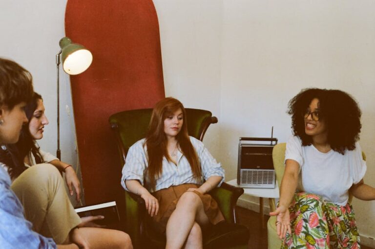 Four adults engaged in a relaxed group discussion in a cozy indoor space.
