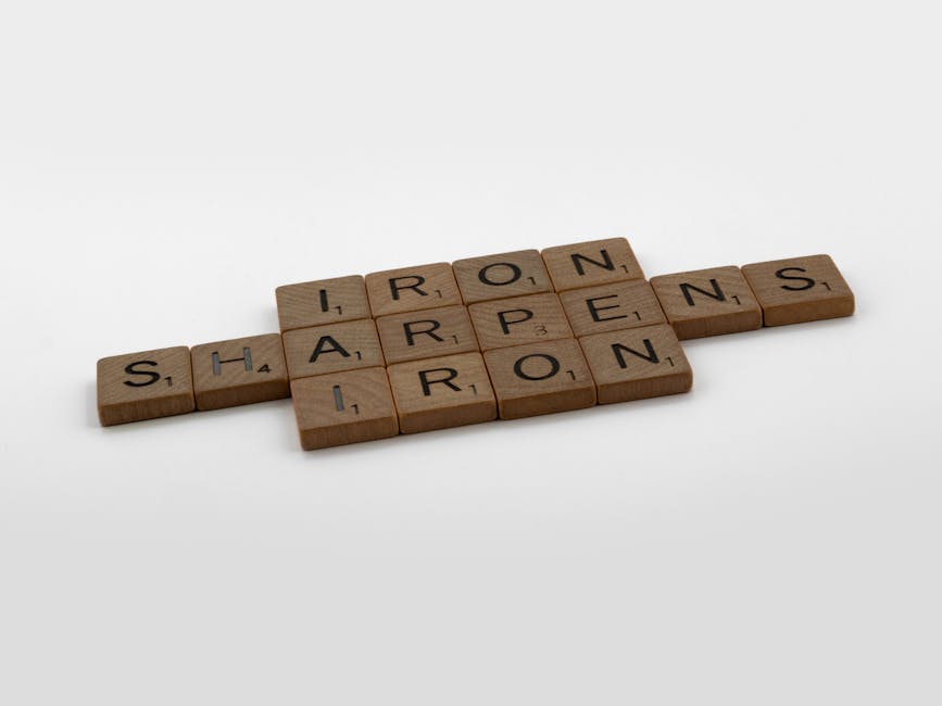 Scrabble tiles forming the phrase 'Iron Sharpens Iron' on a plain background.