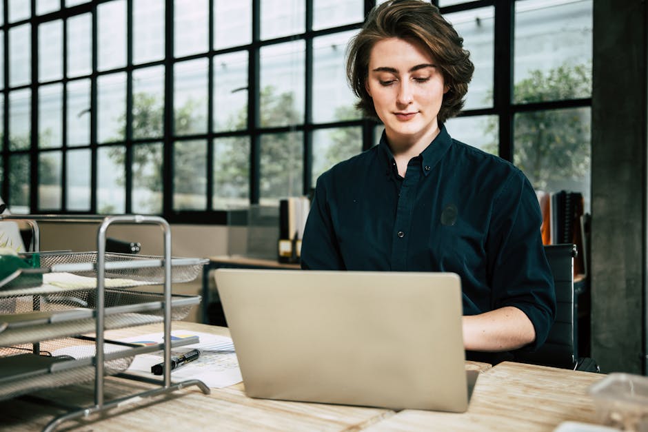 Professional woman using laptop in a stylish office environment, focused on work.