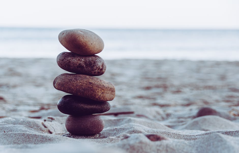 Peaceful scene of carefully balanced stacked stones on a sandy beach, evoking calmness and tranquility.