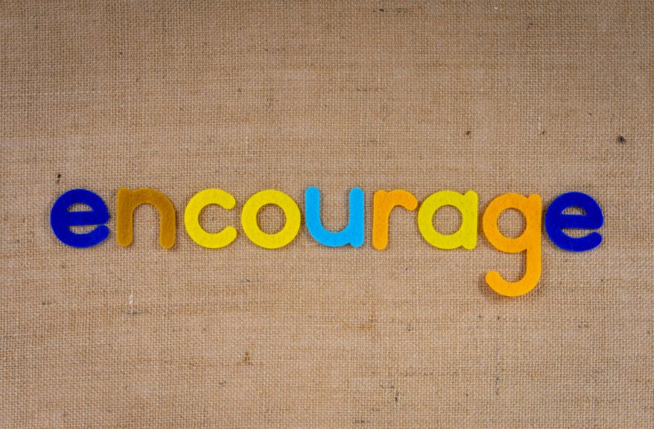The word 'encourage' in colorful letters on a brown burlap texture, conveying positivity and motivation.