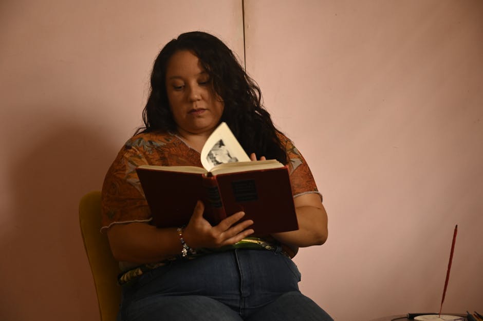 A woman engrossed in reading a book while seated indoors, creating a serene and focused atmosphere.