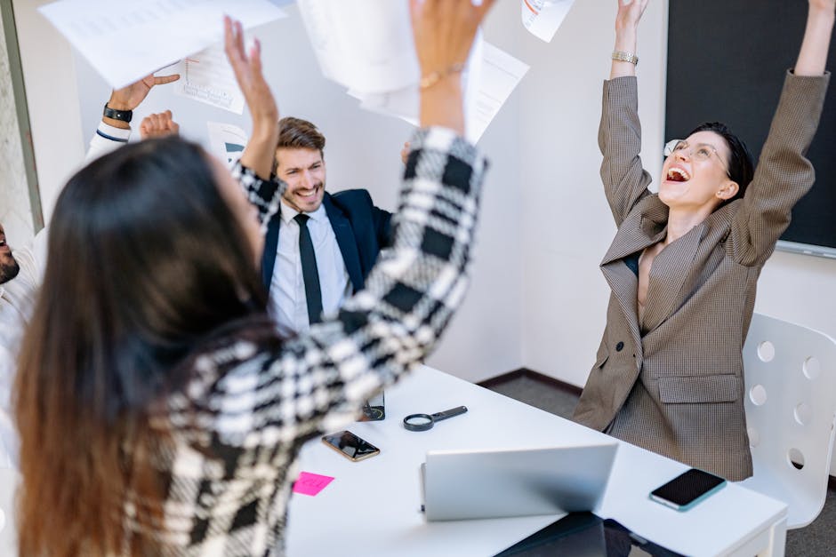 Diverse business team celebrating success with joy in a modern office setting.