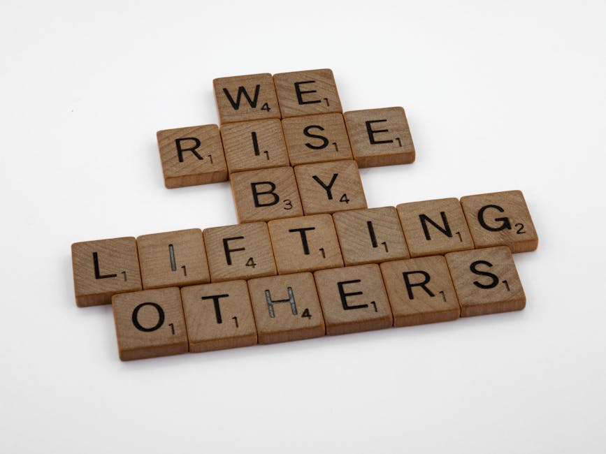Scrabble tiles forming the quote 'We rise by lifting others' on a white background.