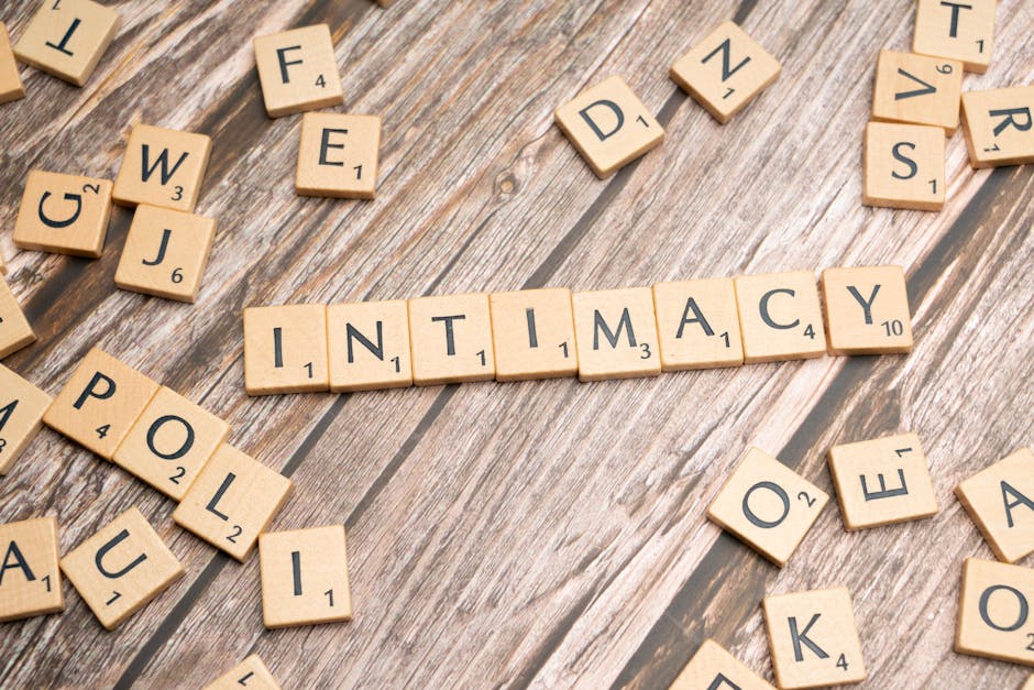 Scrabble tiles arranged to form the word 'intimacy' on a wooden background.