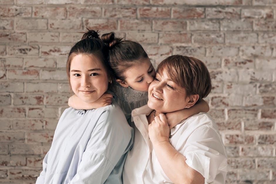 A warm family portrait of a mother with her two daughters sharing affection and smiles.