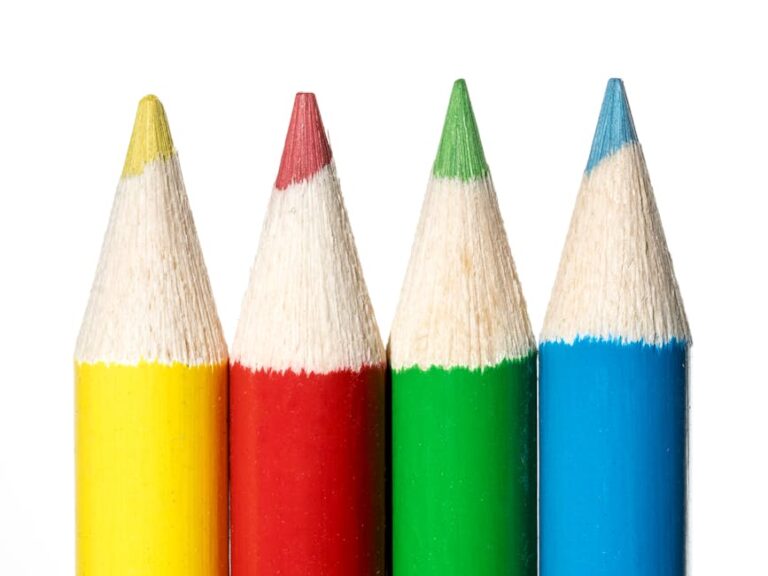 Vibrant close-up of colored pencils with yellow, red, green, and blue hues on a white background.