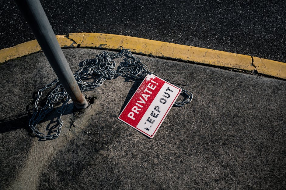 A chained 'Private Keep Out' sign lies on an urban sidewalk, emphasizing security.