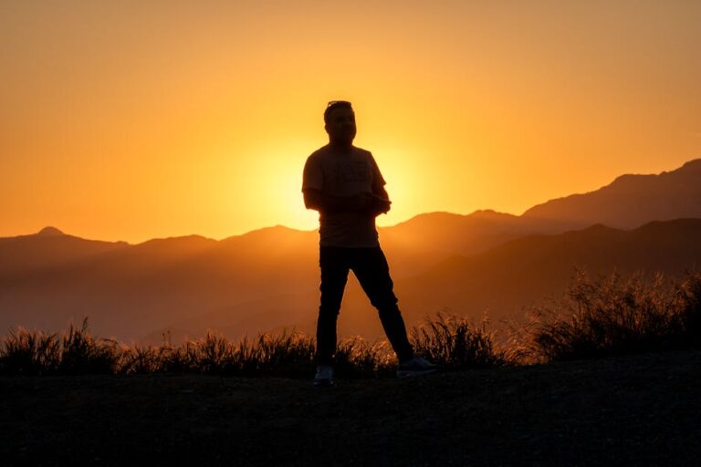 A silhouette of a person on Mount Baldy at sunset, capturing the vibrant orange sky.