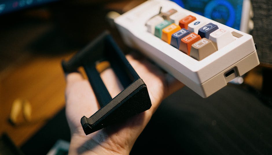 Detailed view of a mechanical keypad with colorful keys held in a hand, showing electronic accessories.