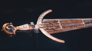 Close-up of an intricately designed historical sword with ornate details on blade and hilt.