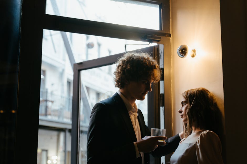 Elegant couple enjoying a romantic evening with drinks by a restaurant door.