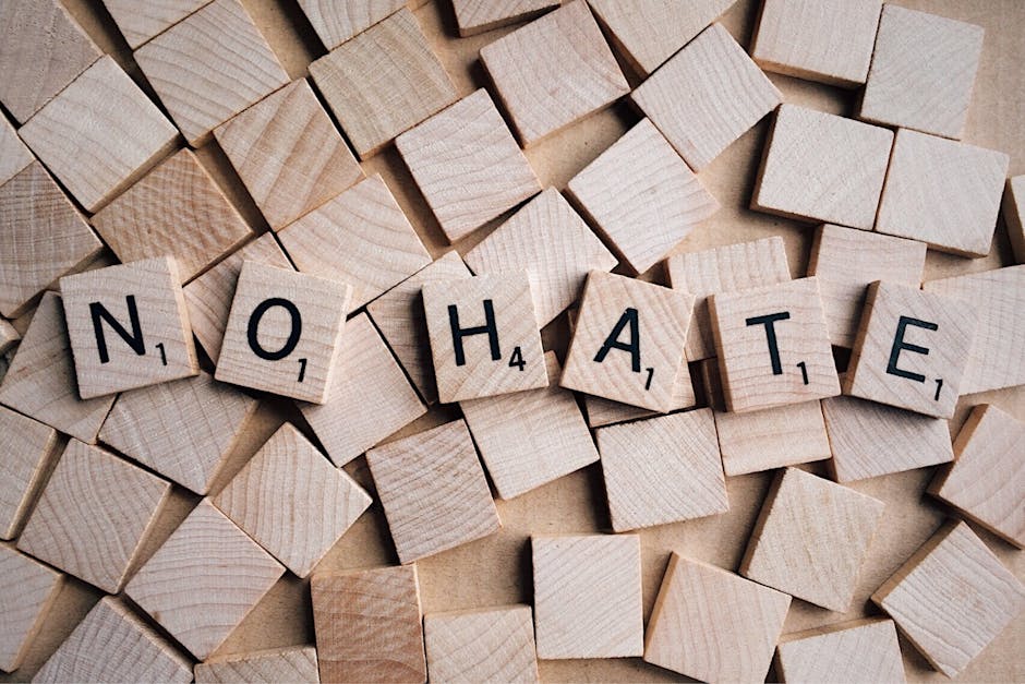 Overhead shot of wooden scrabble tiles forming the phrase 'No Hate', emphasizing a message of inclusivity.